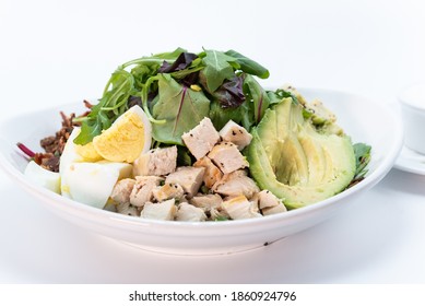 Overhead View Of Cobb Salad Piled High With Sliced Avocado, Tomato, Chicken, Hard Boiled Egg, And Arrugula.