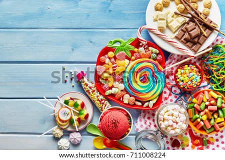 Overhead view of colorful array of different childs sweets and treats in bowls on light blue wood background
