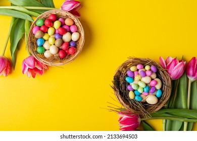 Overhead View Of Colorful Easter Eggs And Candies In Nests With Tulips On Yellow Background. Unaltered, Cultures, Festival, Craft, Sweet Food, Candy, Decoration And Celebration Concept.