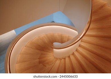 An overhead view of a contemporary spiral staircase with a flawless white balustrade and warm wooden steps that elegantly twist downwards, creating a mesmerizing architectural pattern. - Powered by Shutterstock