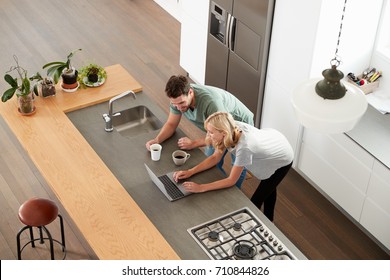 Overhead View Of Couple Looking At Laptop In Modern Kitchen