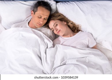 Overhead View Of Couple Sleeping In Bed At Home