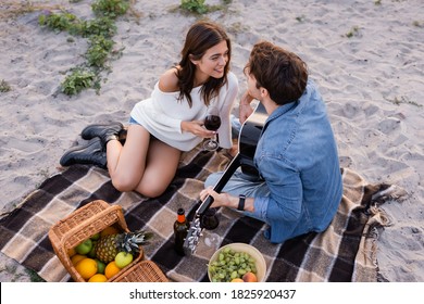 Overhead View Of Couple With Wine And Acoustic Guitar Sitting On Beach During Picnic