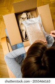 Overhead View Of Curious Woman Unboxing In The Living Room New Delivery Of E-commerce Ordered Goods Via Internet - Plastic Bubble Warping Protection Film Cardboard Box