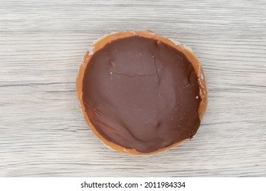 Overhead View Of Custard Raised Donut Is Textured With Chocolate Coating For A Sweet Treat Delight.