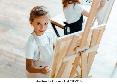 Overhead View Of Cute Kid Looking At Camera In Art School 