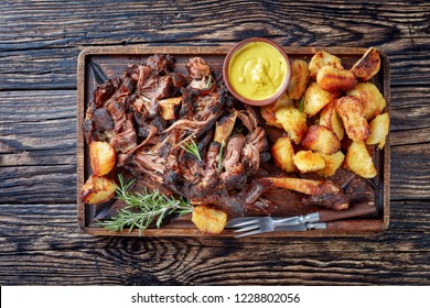 Overhead View Of Delicious Slow Roast Tender Leg Of Lamb Pulled Off The Bones And  Served With Crispy Roast Potatoes On A Wooden Tray On A Rustic Wooden Table,view From Above, Flatlay