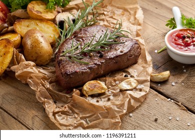 Overhead View Of Delicious,grilled Beef Steak With Roasted Potatoes And Fresh Green Herb Salad On An Old Wooden Table