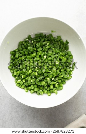 Overhead view of diced green beans, top view of green beans, sliced haricot verts on a white countertop, process of making nigerian fried rice