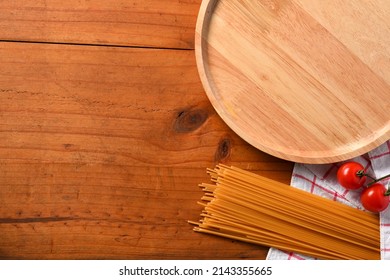 Overhead View, Dining Table Setting Mockup With Spaghetti Ingredients. Empty Wooden Plate And Copy Space On Wooden Background.