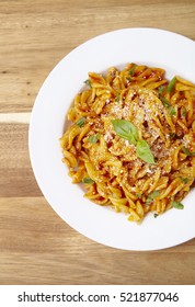 Overhead View Of A Dinner Dish Full Of Tomato And Basil Fusilli Pasta On A Wooden Kitchen Counter Background