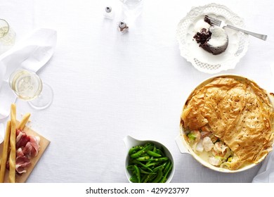 Overhead View Of Dinner Table With Chicken And Leek Pie, Green Beans And Chocolate Pudding Dessert