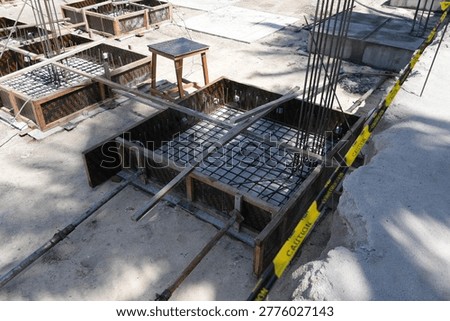 An overhead view displays multiple square wooden formworks, each containing an intricate steel rebar cage, prepared for the next stage of concrete foundation work.