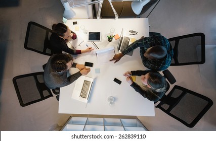 Overhead view of diverse team analyzing data while sitting at office. Multiracial business people in a meeting working on new project. - Powered by Shutterstock