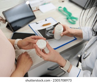 Overhead view of doctor gynecologist obstetrician prescribing prenatal vitamins and nutritional supplement to a pregnant woman in a gynecological clinic. Pregnancy. Maternity. Healthcare and medicine