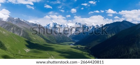 Overhead View of Dramatic Snow Capped Mountain Range Valley Green Meadow and Blue Sky