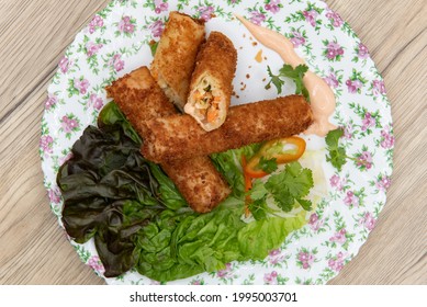 Overhead View Of Earty Appetizer Of Breaded, Deep Fried Egg Rolls Full Of Vermicelli And Vegetables Served On A Flowered Plate.