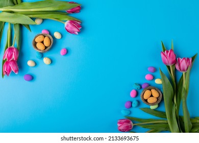 Overhead View Of Easter Candies In Small Nests With Pink Tulips On Blue Background With Copy Space. Unaltered, Cultures, Festival, Craft, Sweet Food, Candy, Decoration And Celebration Concept.