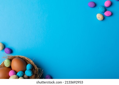 Overhead View Of Easter Eggs With Colorful Candies In Nest On Blue Background With Copy Space. Unaltered, Cultures, Festival, Craft, Sweet Food, Candy, Decoration And Celebration Concept.