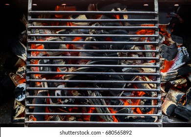 Overhead View Of Empty BBQ Hot Fire Grill And Burning Charcoal Briquettes With Bright Flames. Outdoor Scene. Concept for Summer Party Or Picnic Or Cookout. Isolated Black Background. Close Up