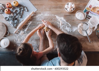 'Overhead View Of Father And Daughter Kneading Dough At Kitchen Table