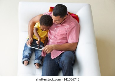 Overhead View Of Father And Son On Sofa Using Digital Tablet - Powered by Shutterstock