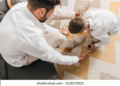 Overhead View Of Father Teaching Son To Tying Shoelaces At Home