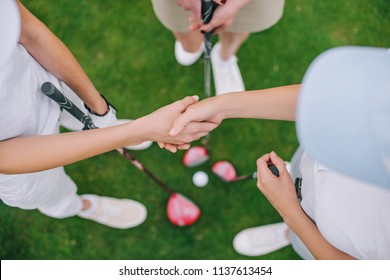 Overhead View Of Female Golf Players With Golf Clubs Shaking Hands While Standing On Green Lawn