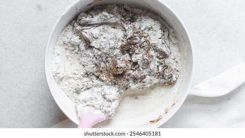 Overhead view of flour being mixed into molasses cookie dough, top view of gingerbread cookie dough in a white mixing bowl, process of making christmas cookies - Powered by Shutterstock