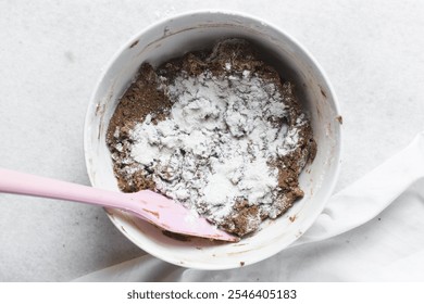 Overhead view of flour being mixed into molasses cookie dough, top view of gingerbread cookie dough in a white mixing bowl, process of making christmas cookies - Powered by Shutterstock