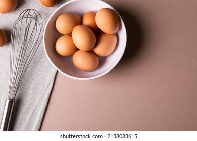 Overhead View Of Fresh Brown Eggs In Bowl By Wire Whisk On Table With Copy Space. Unaltered, Food, Healthy Eating Concept.