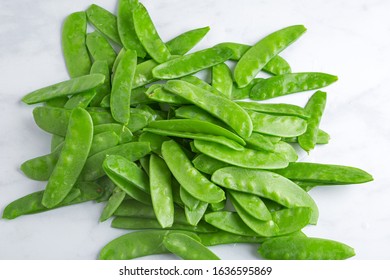 Overhead View Of Fresh Raw Sugar Snap Peas On A Light Marbled Surface