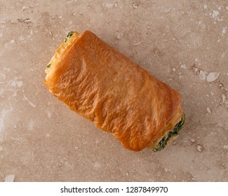 Overhead View Of A Freshly Baked Pastry With A Spinach Filling On A Marble Counter Top.