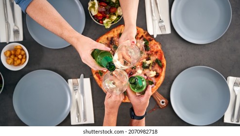 Overhead View Of Friends Making Toast Sitting Around Table In Pizza Restaurant - Powered by Shutterstock