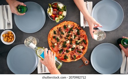 Overhead View Of Friends Sitting Around Table In Pizza Restaurant Drinking Wine