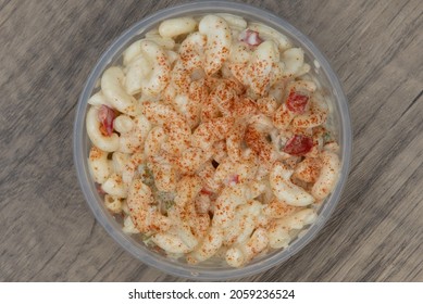 Overhead view of generous portion side order of macaroni salad in a clear plastic bowl to compliment your meal.