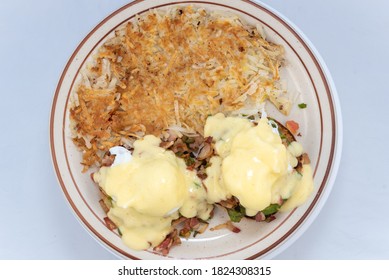 Overhead View Of Generous Serving Meal Of A Hearty Eggs Benedict Stacked Tall With Toppings And Dripping With Melted Cheese.