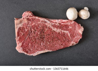 Overhead View Of A Gourmet Raw Rib Steak With Seasonings And Mushrooms On A Granite Countertop