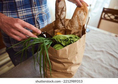 Overhead View Of A Guy Sorting Organic Fresh Vegetables While Unpacking Grocery Shopping Bag In The Kitchen At Home. Food Delivery. Healthy Grocery Purchasing In Farmers Markets And Stores