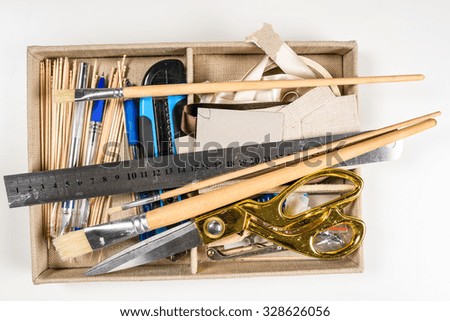 Overhead view of hand tools placed in box (aluminum ruler, scissors, wooden brushes etc.)