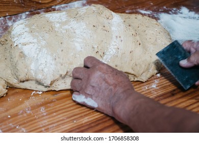 Overhead View Of The Hands Of An Adult Man Kneading Dough In A Wooden