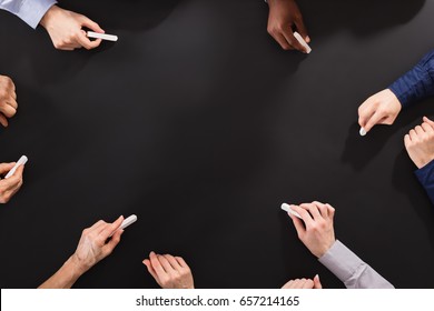 Overhead View Of Hands Drawing With Chalk On Blackboard