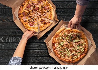 Overhead View Of Hands Taking Pizza From Cardboard Box