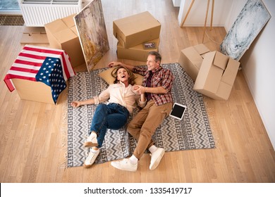 overhead view happy couple laying floor surrounded by cardboard boxes 