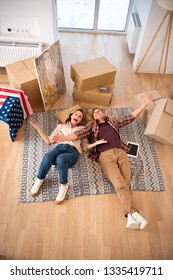 overhead view happy excited couple laying floor at new home