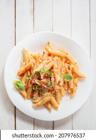Overhead View Of A Healthy Plate Of Italian Penne Pasta With Basil, Savory Spicy Sauce And Grated Parmesan Cheese On Rustic White Wooden Boards With Copyspace