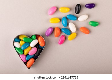 Overhead view of heart shape container with multi colored candies on white background. unaltered, sweet food and unhealthy eating concept. - Powered by Shutterstock