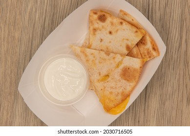 Overhead View Of Hearty Appetizer Of Quesadilla Wedges With Melted Cheese And Sour Cream As A Dipping Sauce.