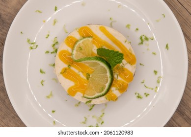 Overhead View Of Hearty Key Lime Pie Decorated With Icing, Lime Slice, And Mint Leaf.