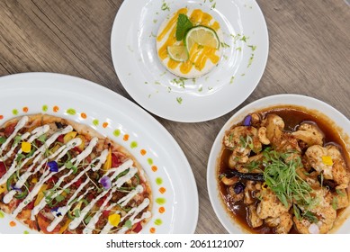 Overhead View Of Hearty Table Of Flat Bread Pizza, Key Lime Pie, And Tangy Roasted Cauliflower On A Wooden Surface.